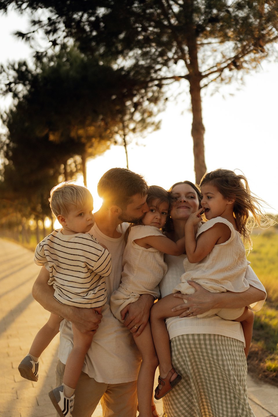 Parents and their three children standing on a paved path.